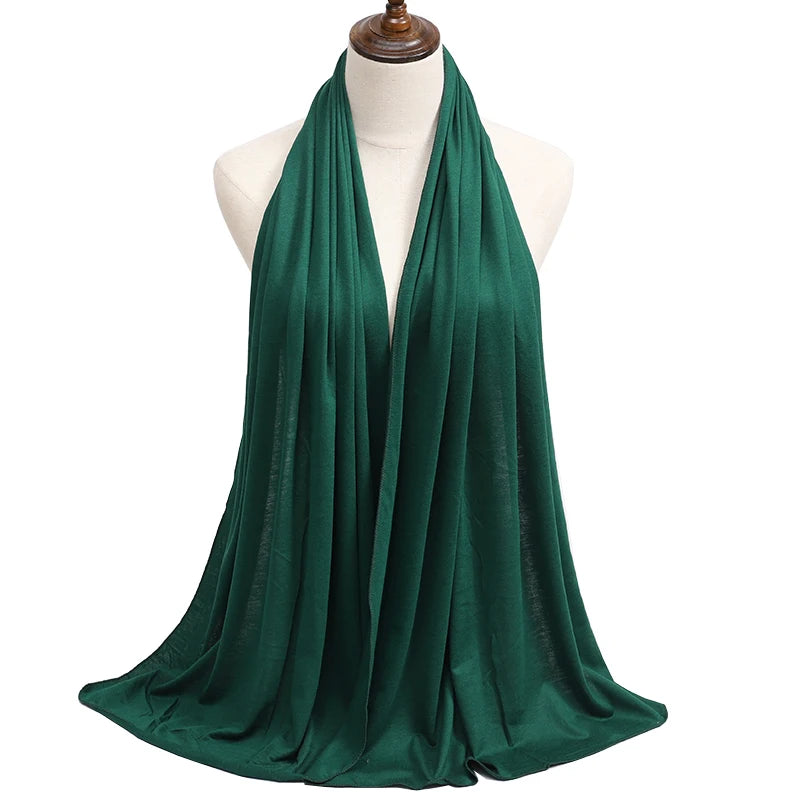 A deep emerald green premium modal jersey hijab draped around a mannequin's neck.