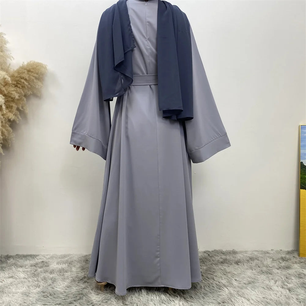 Lange, fließende graue Maxi-Abaya mit dunkelblauer Draperie, getragen drinnen.