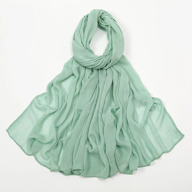 Écharpe en crêpe rayon vert menthe clair drapée autour du cou et flottant sur les épaules.