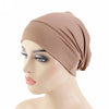 Un mannequin porte un bonnet foulard beige et extensible sur sa tête.