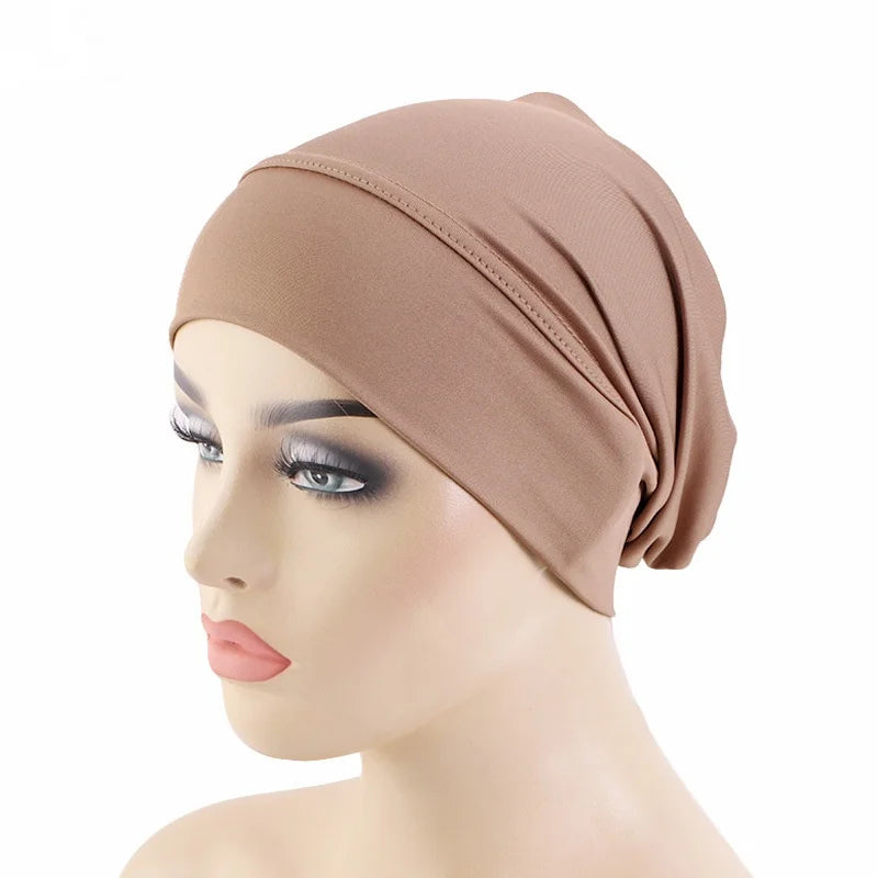 Un mannequin porte un bonnet foulard beige et extensible sur sa tête.