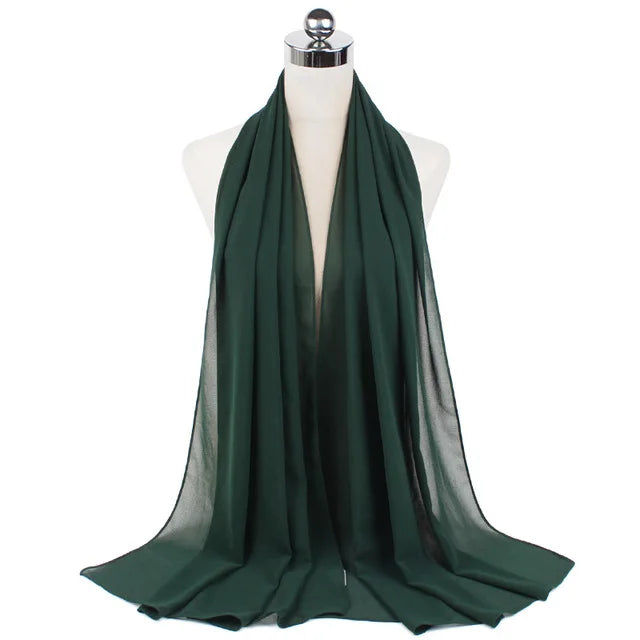 A dark emerald green chiffon hijab scarf draped over a mannequin.