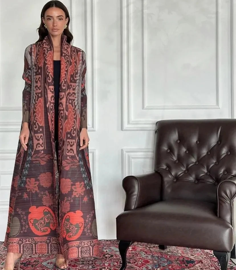 Una mujer modela un largo abrigo maxi estampado vintage con cuello desmontable en tonos óxido y negro contra una pared blanca