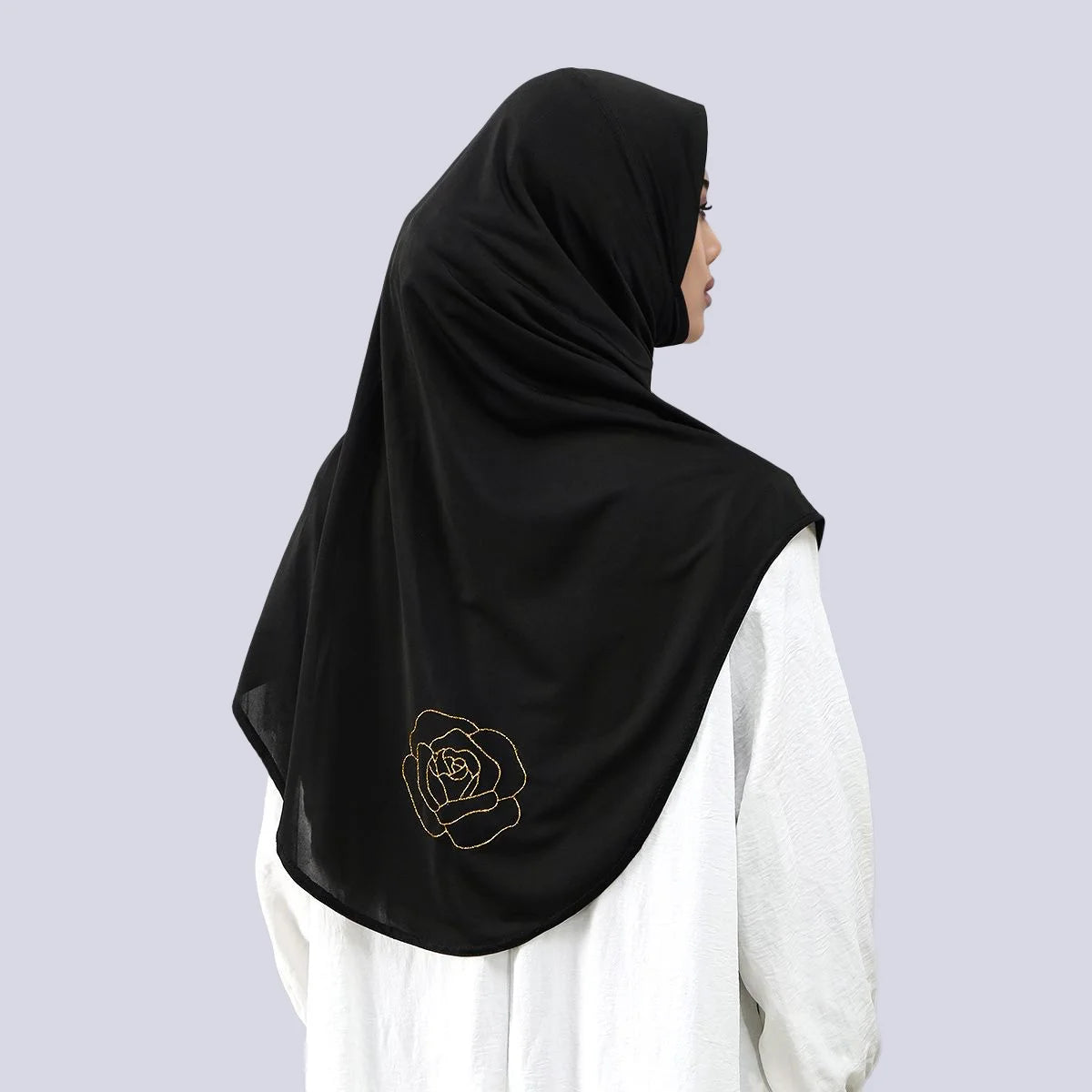 Écharpe hijab noire avec un motif de rose brodée dorée portée par une femme.
