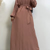 Eine Frau trägt einen staubrosa marokkanischen Kaftan-Abaya mit langen Ärmeln und einem gebundenen Bund.