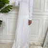 Langes weißes, elegantes Abaya-Kleid mit langen Ärmeln und hohem Ausschnitt vor einer weißen Wand