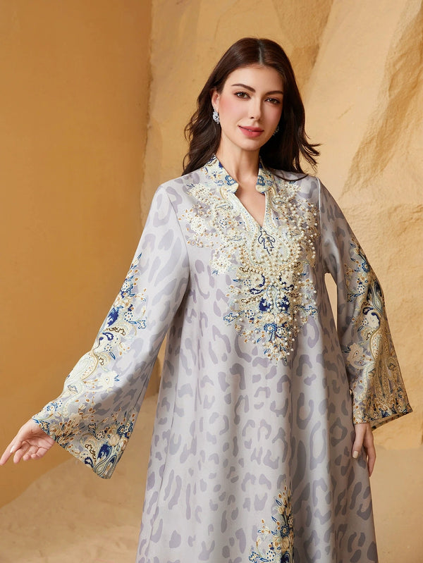 A woman models a light gray leopard print abaya with blue and gold diamond embellishments.