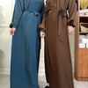 Eine Frau modelliert ein langes, fließendes marokkanisches Kaftan-Abaya in dunkelgrünen und braunen Tönen.