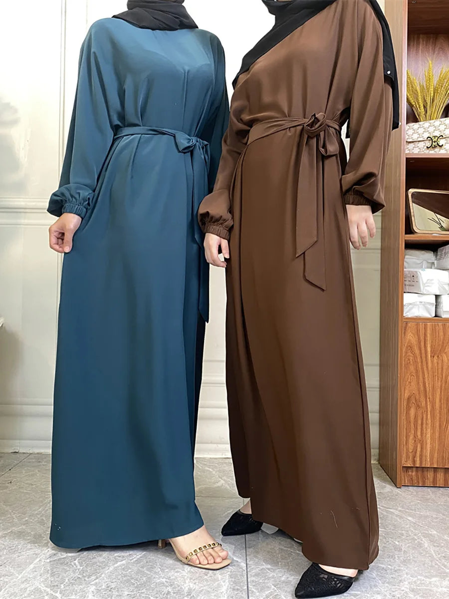 Eine Frau modelliert ein langes, fließendes marokkanisches Kaftan-Abaya in dunkelgrünen und braunen Tönen.