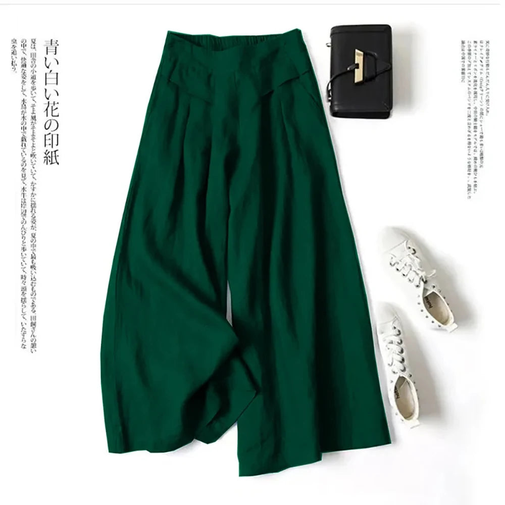 Dunkelgrüne Leinenmischhose mit weit geschnittenen Palazzo-Beinen neben einer schwarzen Clutch und weißen bestickten Schuhen.