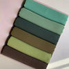 Ein Set von sechs pastellfarbenen Chiffon-Hijabs in verschiedenen Grüntönen und Olivfarbe, ausgelegt in einer Box.