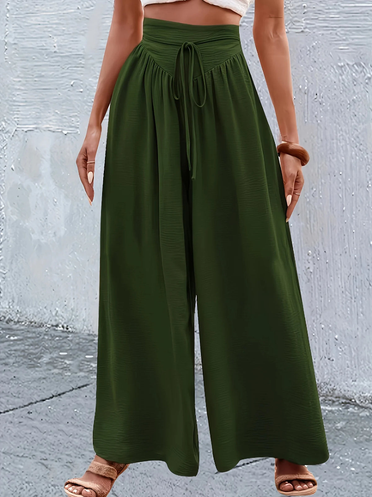 Un mannequin portant un pantalon large vert olive à taille élastique avec des détails en dentelle