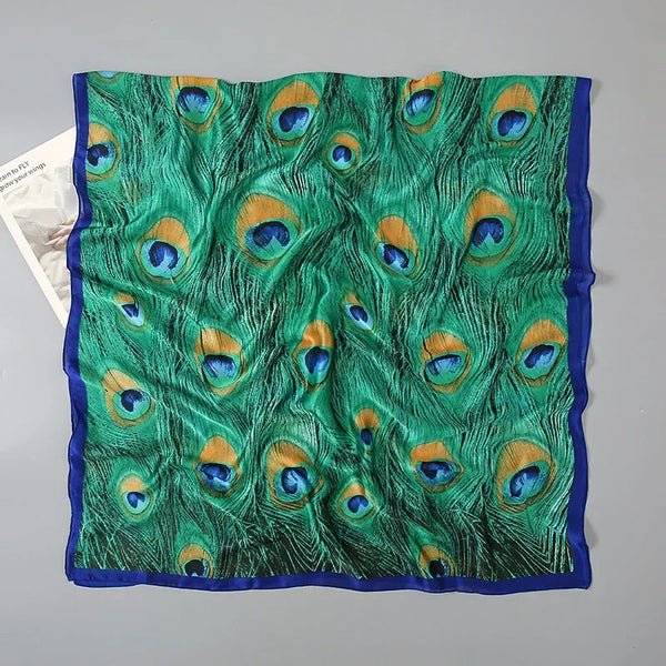 A vibrant green silk pareo scarf featuring a pattern of peacock feather designs with blue and gold accents.