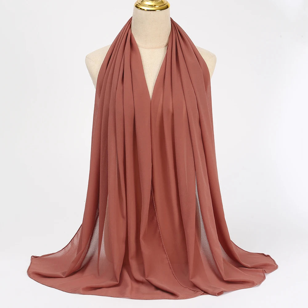Ein drapierter, fester Terrakotta-Chiffon-Hijab-Schal auf einem Mannequin.