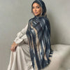 Una mujer vistiendo un pañuelo hijab de acuarela azul oscuro y beige con una blusa blanca.