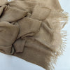 Écharpe hijab en coton viscose beige avec franges et pompon, drapée sur une surface blanche.