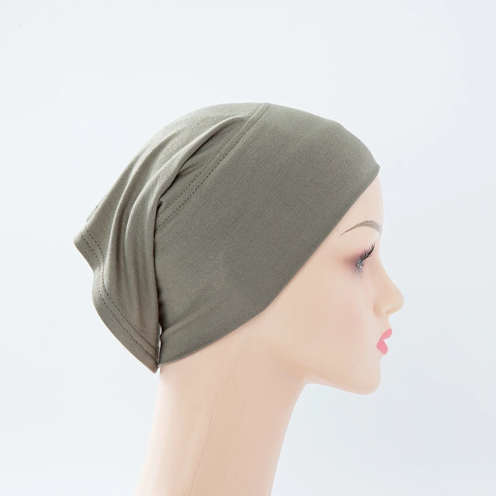 Nahaufnahme einer salbeigrünstigen Bambus-Jersey-Turbanmütze auf einem Mannequin-Kopf.
