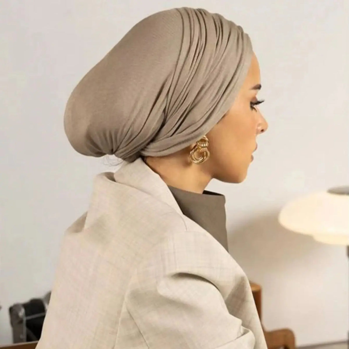 Femme portant un instant hijab en jersey modal beige et un blazer beige clair, vue de profil.