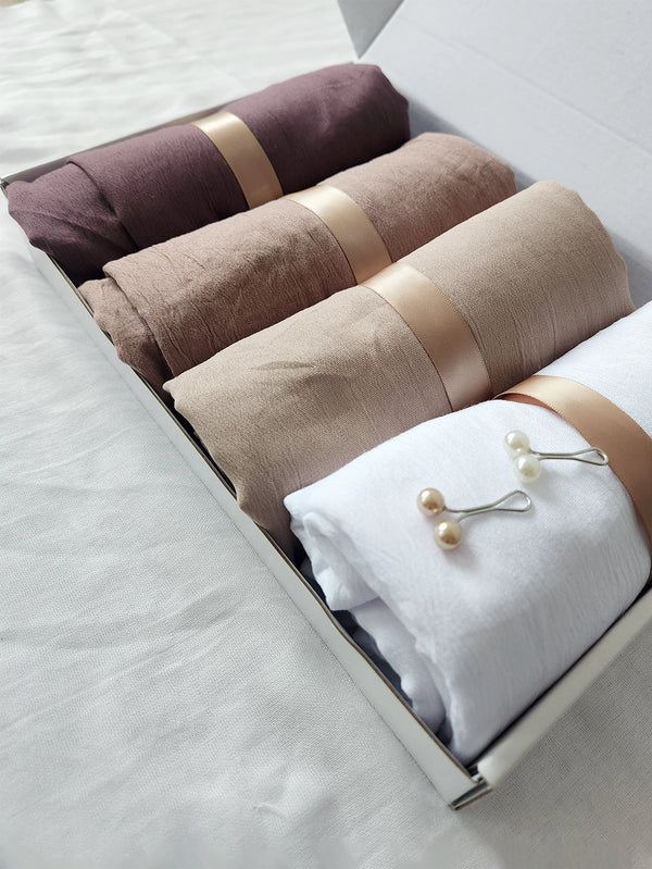A pack of four crinkled scarves or hijabs in shades of brown and beige are displayed in a box.