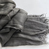 Foulard hijab en viscose coton gris foncé avec pompons, plié et drapé.