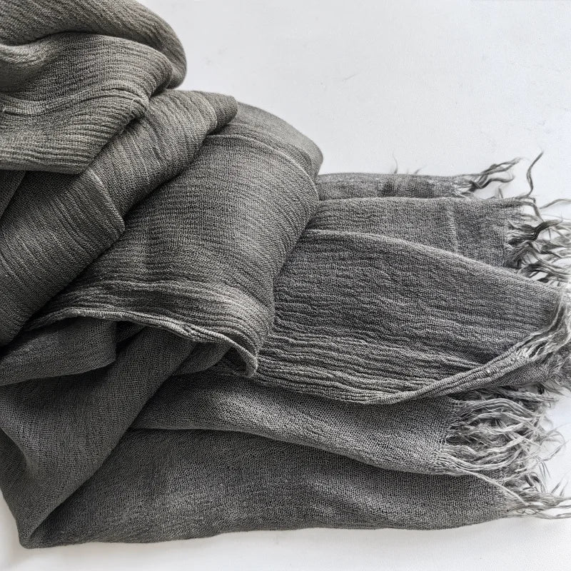 Foulard hijab en viscose coton gris foncé avec pompons, plié et drapé.