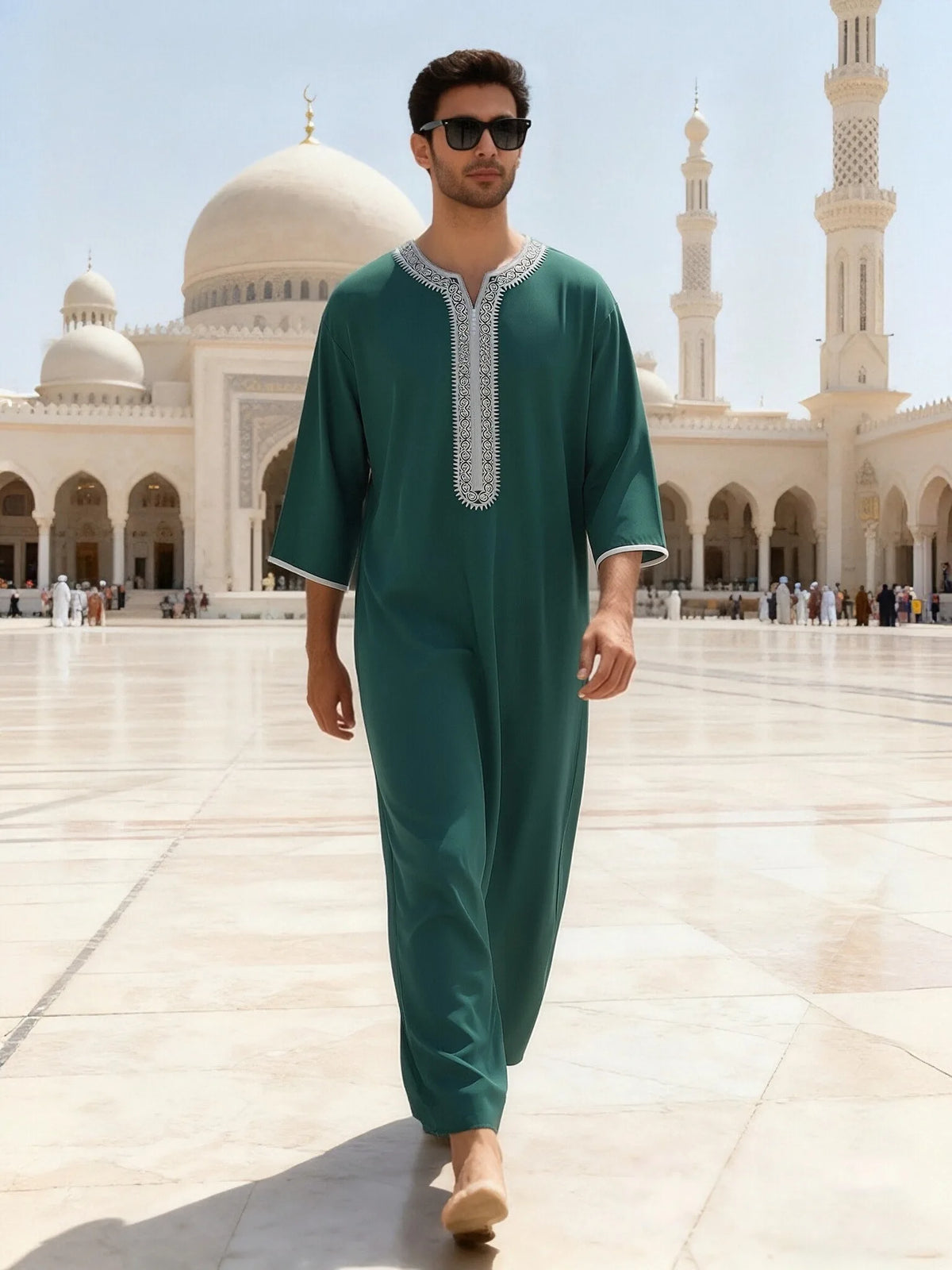 Mann in eleganter smaragdgrüner bestickter muslimischer Robe in einem Hof mit Moscheearchitektur
