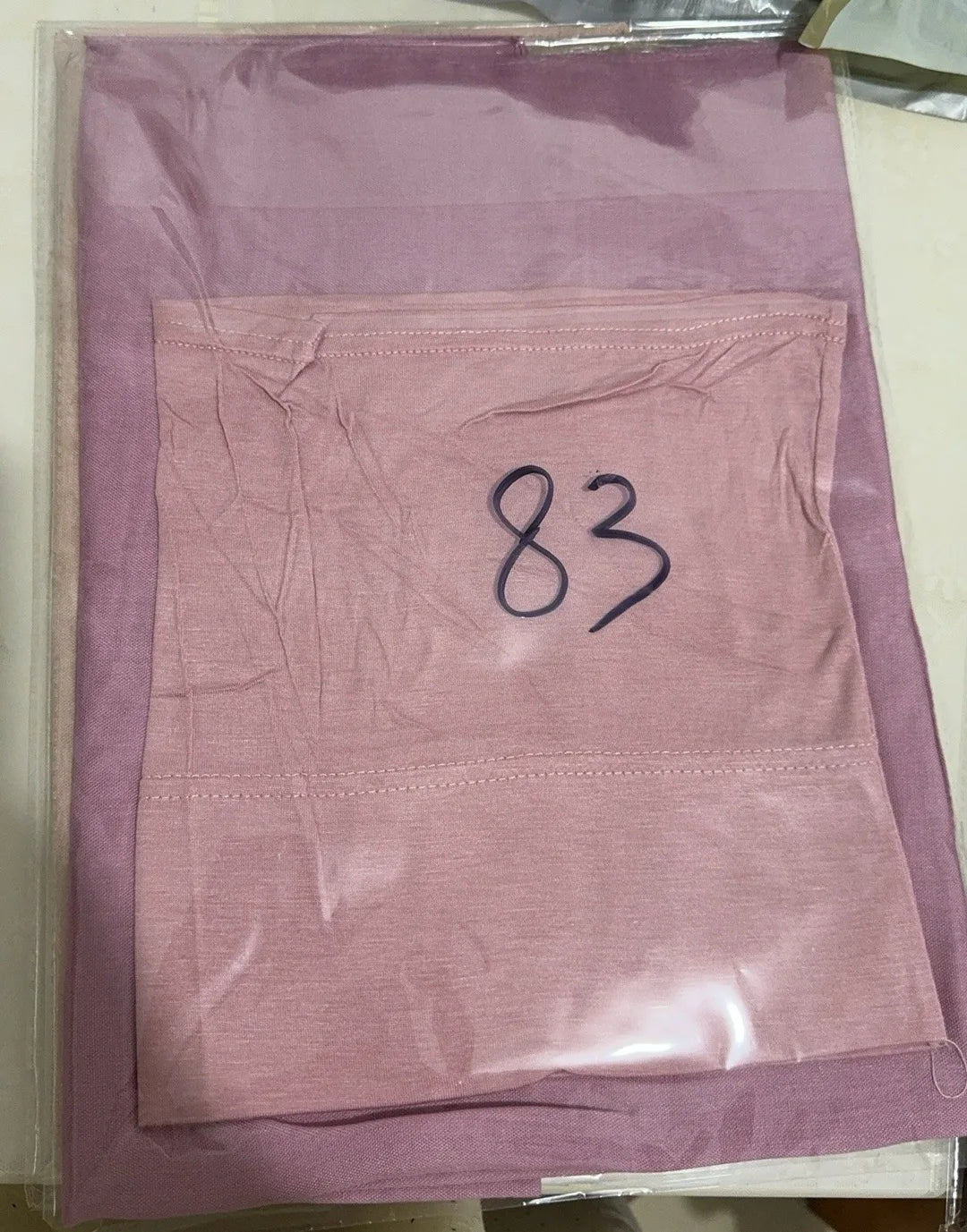 A folded soft lilac hijab set made of modal rayon fabric is visible in clear plastic packaging.