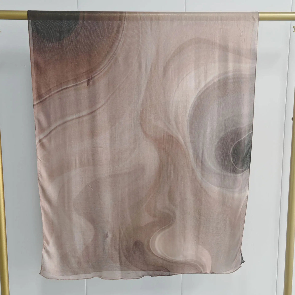 Durchsichtiger, doppelseitiger bedruckter Schal in Beige- und Brauntönen hängt vor hellem Hintergrund.