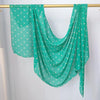Pañuelo hijab de impresión doble cara verde azulada drapeado sobre un percha dorada.