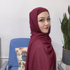 Una mujer vistiendo un conjunto de hijab y chal de chiffon instantáneo color granate, mirando a la cámara.