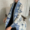 Eine Frau trägt einen weiß-blauen gemusterten, plissierten Abaya-Cardigan über einem schwarzen Oberteil.