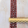 Cinta de jacquard geométrica roja y blanca con regla de madera festoneada sobre fondo blanco