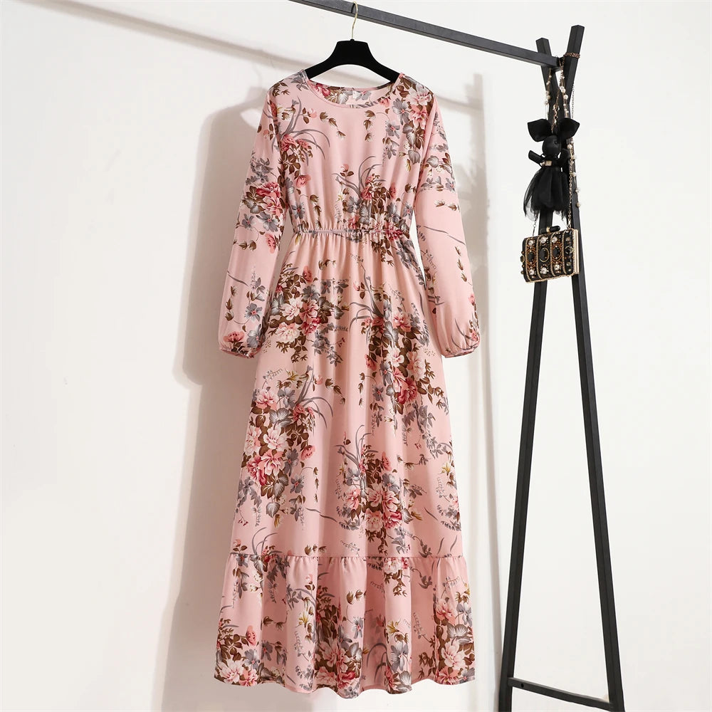 Rosa Blumenmuster-Maxikleid hängt an einem schwarzen Haken vor einer weißen Wand.