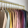 Un présentoir d'abayas de différentes couleurs, suspendues sur un cintre en bois doré.