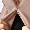 Nahaufnahme eines beigen Chiffon-Instant-Hijabs, der von Händen gegen ein schwarzes Kleidungsstück gefaltet wird.