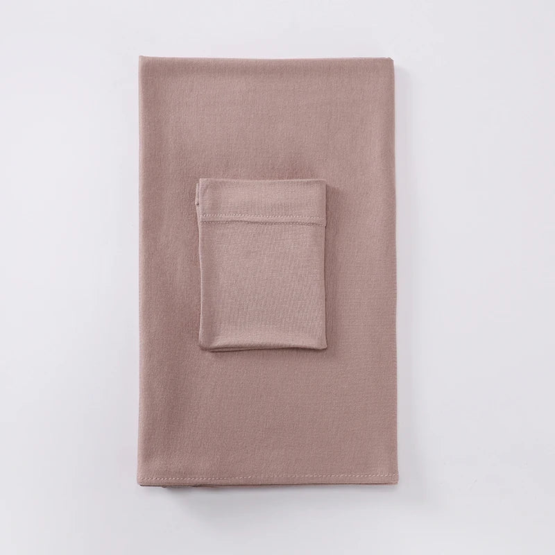 Un conjunto de pañuelo (hijab) a juego de dos piezas doblado en color rosa empolvado.