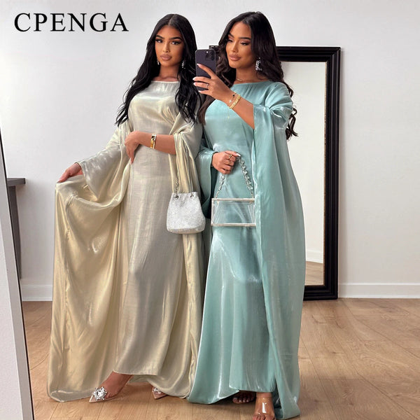 A woman models an elegant, long-sleeve abaya in shimmering champagne and a mint green color.