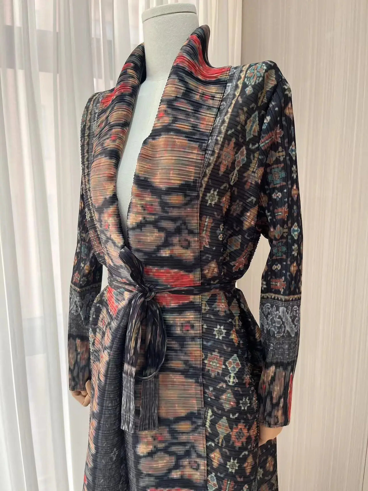 Une femme portant un trench-coat à manches longues à plis à motif foncé exposé sur un mannequin.