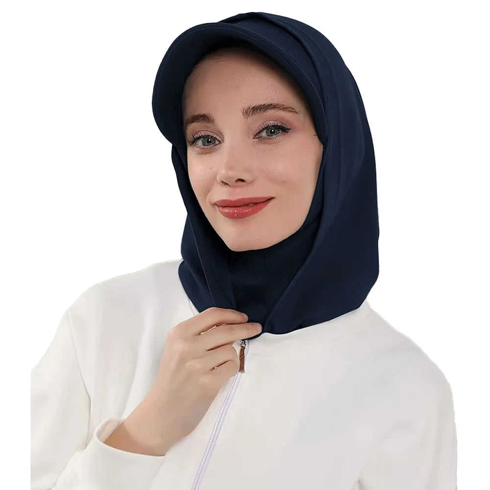 Une femme portant un bonnet hijab couvrant bleu marine et un haut blanc.