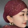 Nahaufnahme einer Frau mit einem eleganten dunkelroten elastischen Turbanhut, verziert mit kleinen Strasssteinen.