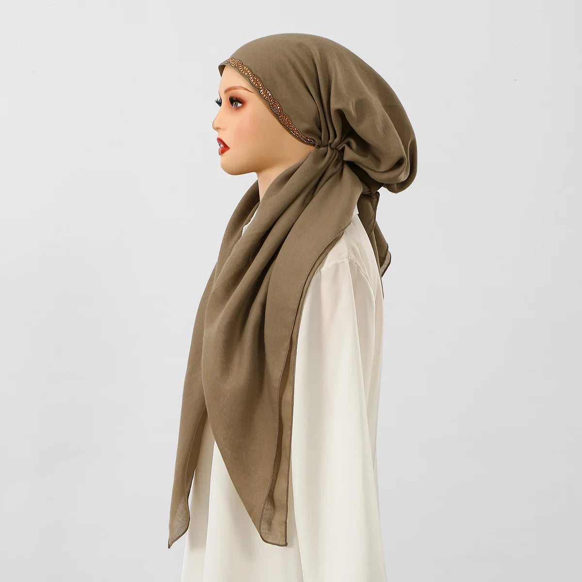 Una mujer vistiendo una diadema elástica de diamantes beige para hijab con una blusa blanca.