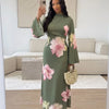 Eine Frau präsentiert ein elegantes Sommer-Blumen-Abaya-Kleid in Olivgrün mit rosa Blumen.