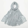 Écharpe châle en rayon gris clair, drapée autour du cou et flottant sur les épaules.
