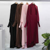 Vier lange, bescheidene Abayas in Schwarz, Braun, Pink und Weinrot hängen an einem Kleiderständer.
