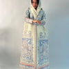 Una mujer vistiendo un cárdigan abaya plisado de color azul claro y blanco con capucha.