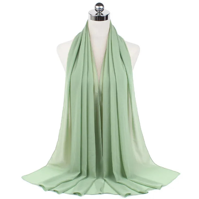 A light sage green chiffon hijab scarf draped on a mannequin.