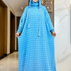 Una mujer vistiendo una abaya azul brillante de algodón con lunares negros y una cubrebocas floral rosa.