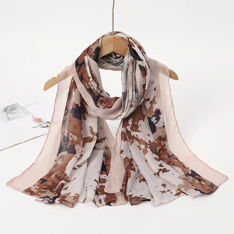 Pañuelo de hijab estampado de leopardo en acuarela beige y marrón colgado en una percha de madera.