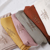 Eine Kollektion von gekräuselten Jersey-Hijab-Schals in verschiedenen Farbtönen wie Beige, Pink, Olivgrün und Rostbraun.