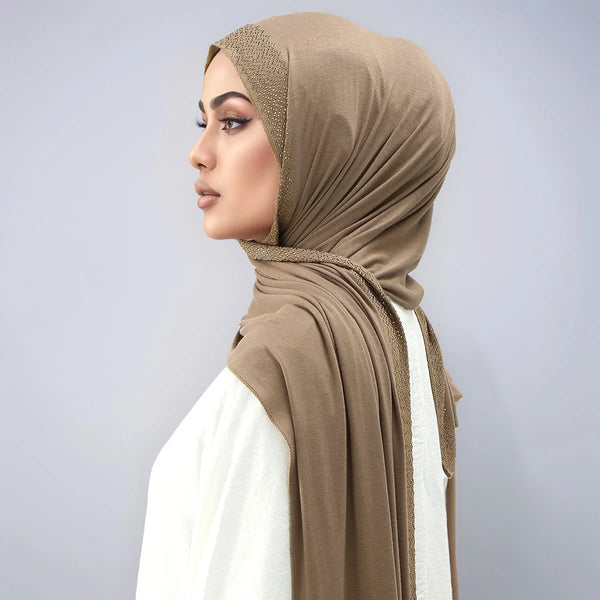 امرأة ترتدي حجاباً من الدانتيل اللامع البيج على رأسها وعنقها.